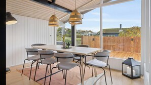 Un espace de salle à manger moderne avec une table en bois, des chaises grises et des luminaires suspendus.