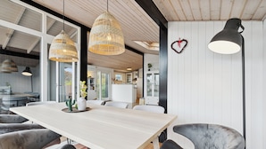 Un espace de salle à manger moderne avec une table en bois, des chaises à revêtement gris et des luminaires suspendus.