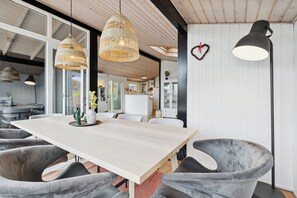 A modern dining area with a wooden table, grey upholstered chairs, and pendant lighting. - Lovely bright cottage near Karrebæksminde (Karrebæksminde)