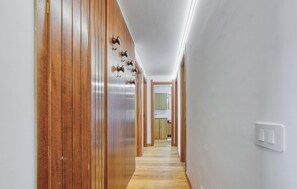 A hallway with wooden doors, a light switch, and a mirror on the wall.
