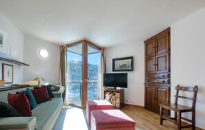 Un salon confortable avec un canapé, un pouf, un meuble en bois et un téléviseur.