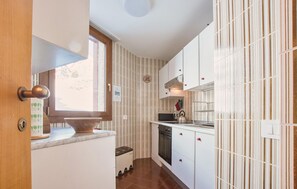 Une cuisine avec des meubles blancs, une fenêtre et un pare-feu en carrelage.