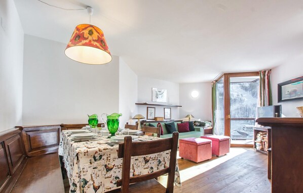Un coin repas avec une table dressée pour quatre personnes, un canapé et une fenêtre donnant sur un beau paysage.