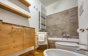 Une salle de bain moderne avec un meuble-lavabo en bois, une baignoire blanche et un espace douche.