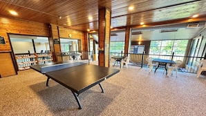 A ping pong table in a room with wooden walls and carpeted floor, surrounded by chairs. - Mountain Getaway | Pool, Hot Tub + Fall Hiking (Lutsen)