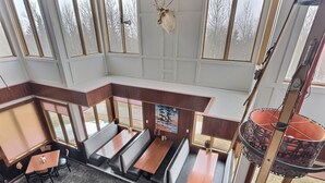 A restaurant with high ceilings, large windows, and a central seating area with booths and tables. - Mountain Getaway | Pool, Hot Tub + Fall Hiking (Lutsen)