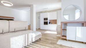 A modern living room with a sofa, a round mirror, and a kitchen area in the background. - 1 bedroom lovely apartment in Recco (Recco)