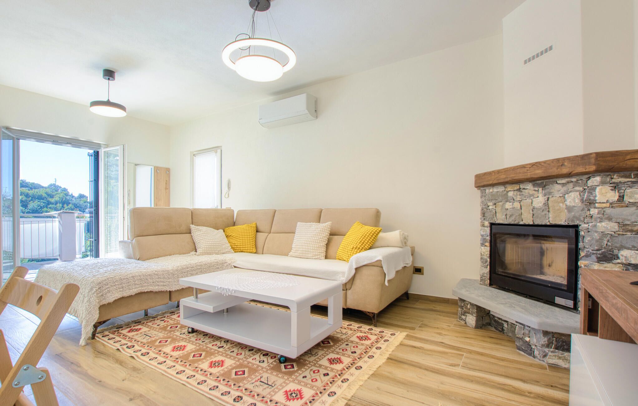 Una sala de estar con sofá, una mesa de centro, chimenea y vistas a través de un ventanal.