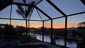 Ein Pool mit Glasabdeckung, eine Palme und Blick auf den Sonnenuntergang.
