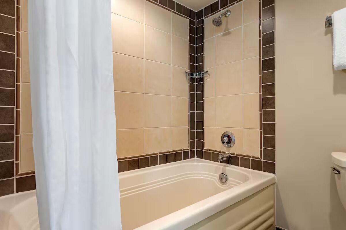 A bathroom with a bathtub, shower, and toilet.