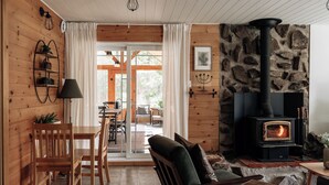 Un intérieur de chalet chaleureux avec un mur en pierre, une cheminée, des meubles en bois et un coin repas.