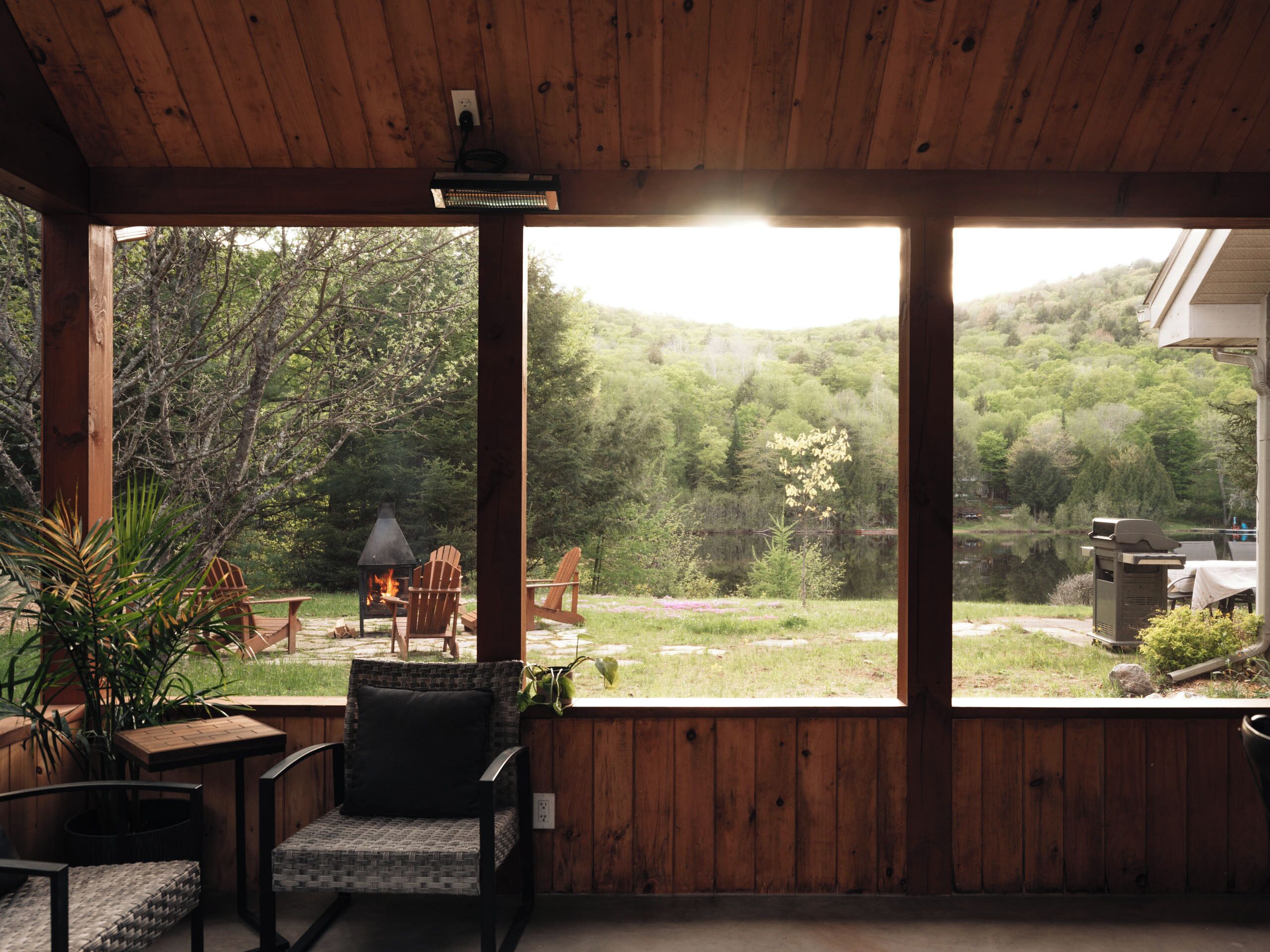 Una terraza de madera con dos sillas Adirondack, una mesa y un brasero.