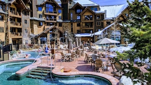 Um resort com várias piscinas, área de estar externa e paisagem coberta de neve.