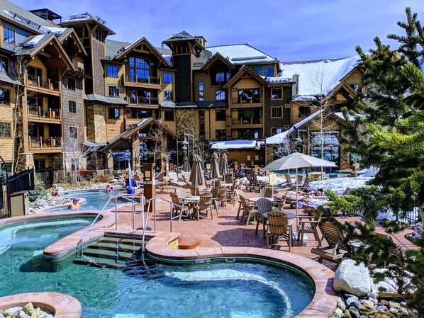 Ein Resort mit mehreren Pools, Sitzgelegenheiten im Freien und verschneiter Landschaft.