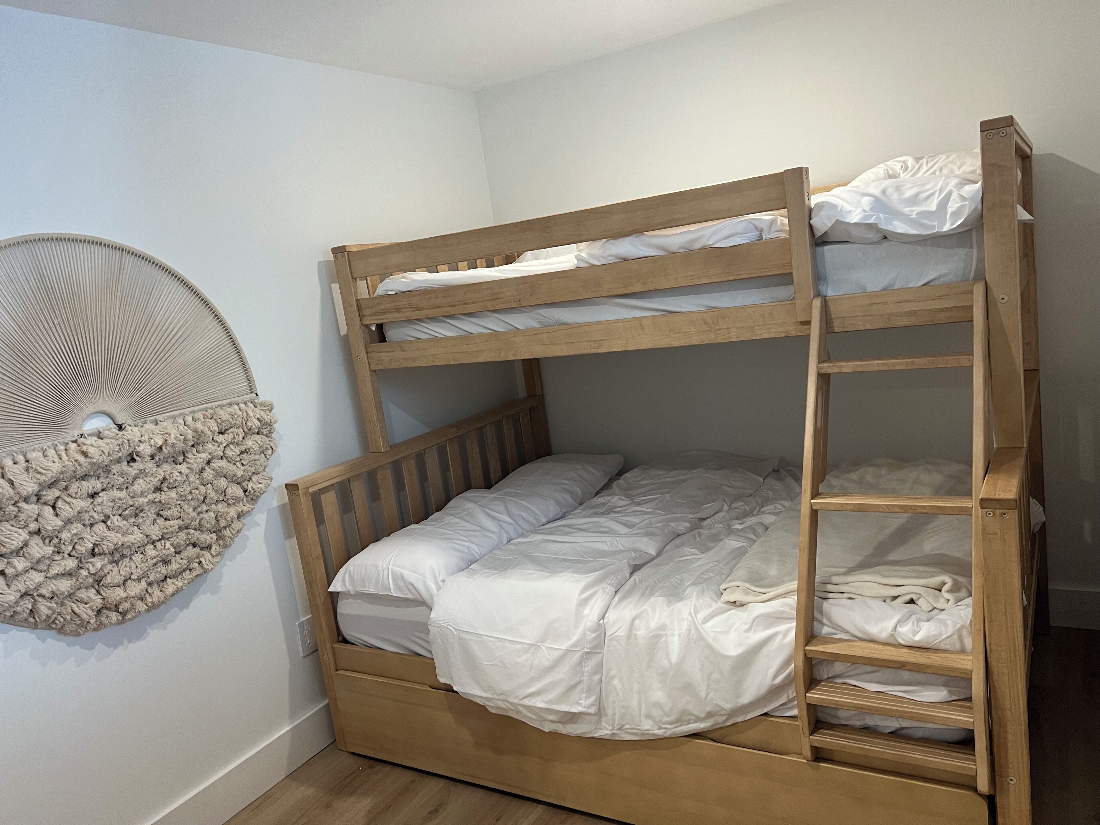 A bunk bed with a wooden frame and white bedding.