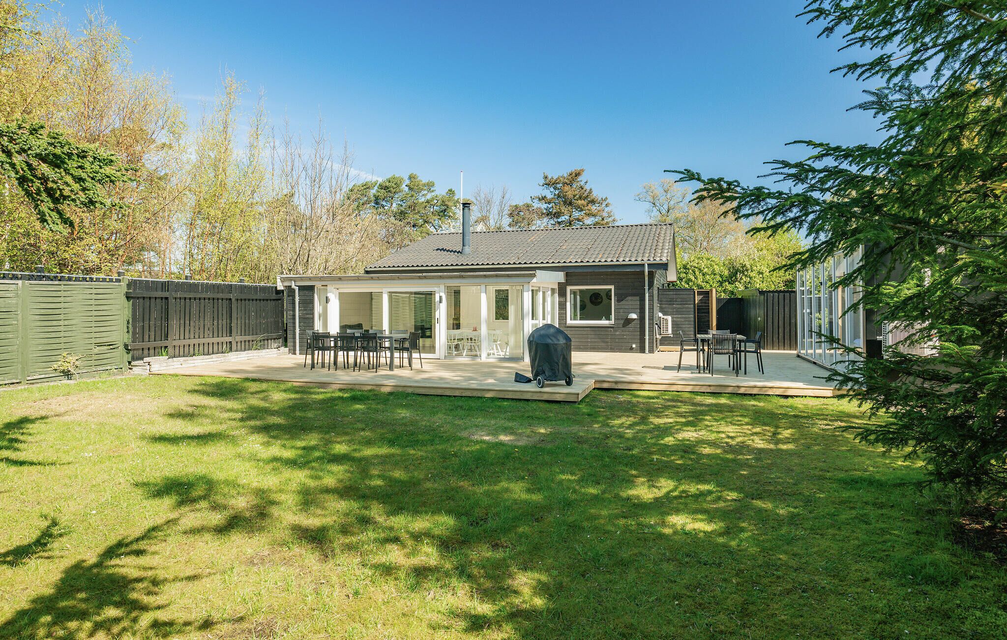 A house with a covered patio, a barbecue area, and a fenced backyard.