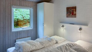 Un dormitorio con cama, una ventana con vistas a la vegetación y un cuadro en la pared.