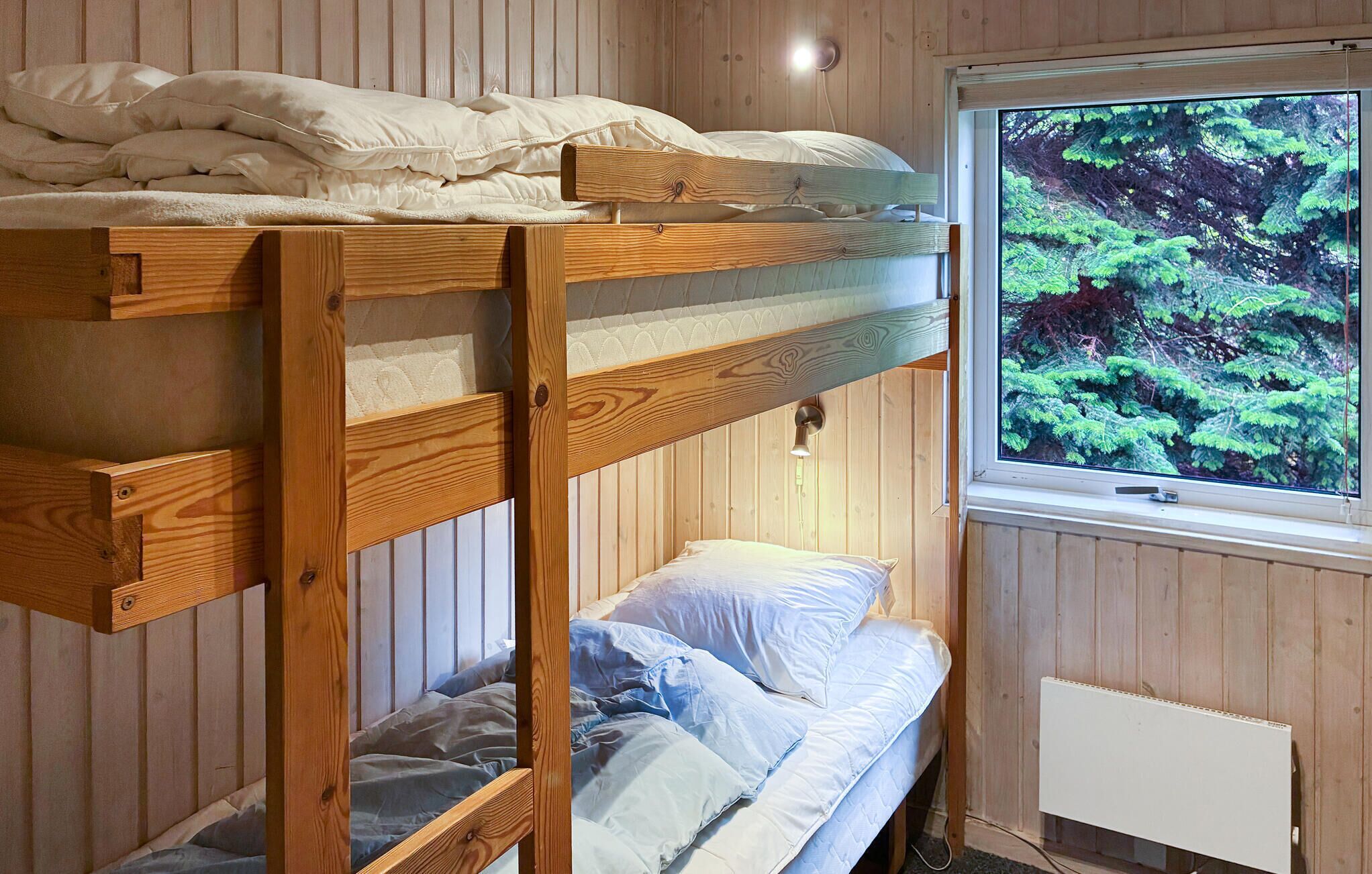 Habitación con literas y ventana con vista a un bosque.