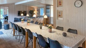 Una cocina moderna con una mesa larga, sillas y un refrigerador.