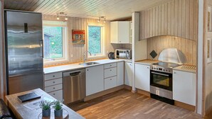 Una cocina moderna con electrodomésticos de acero inoxidable, armarios de madera y un amplio ventanal con vistas a zonas verdes.