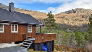 Een houten chalet met een balkon, tegen een bergachtige achtergrond.