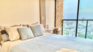 Habitación de hotel con una cama grande, un escritorio y vistas a la ciudad.