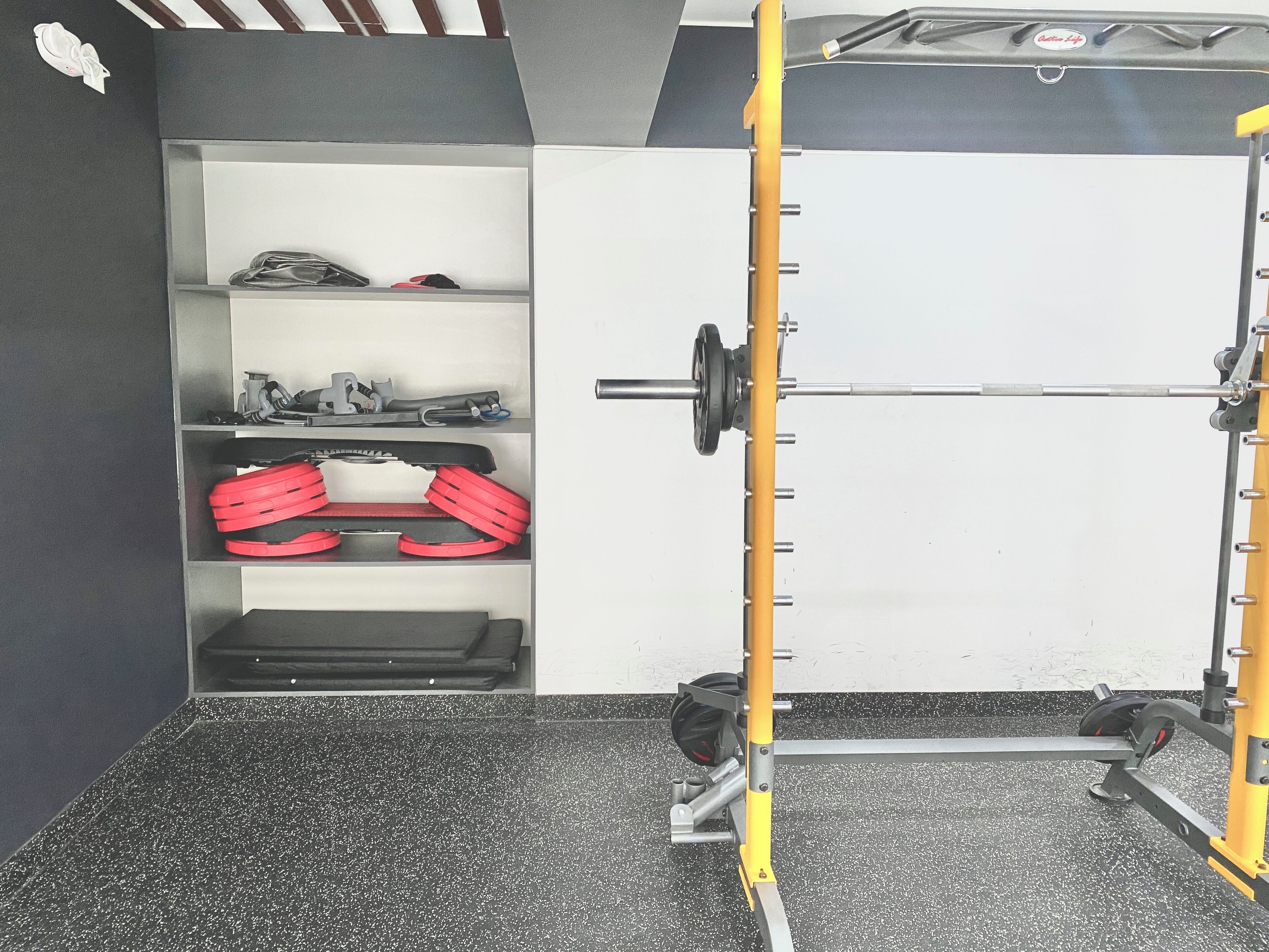 Une salle de sport équipée d’un support à squats, de poids et d’un banc.