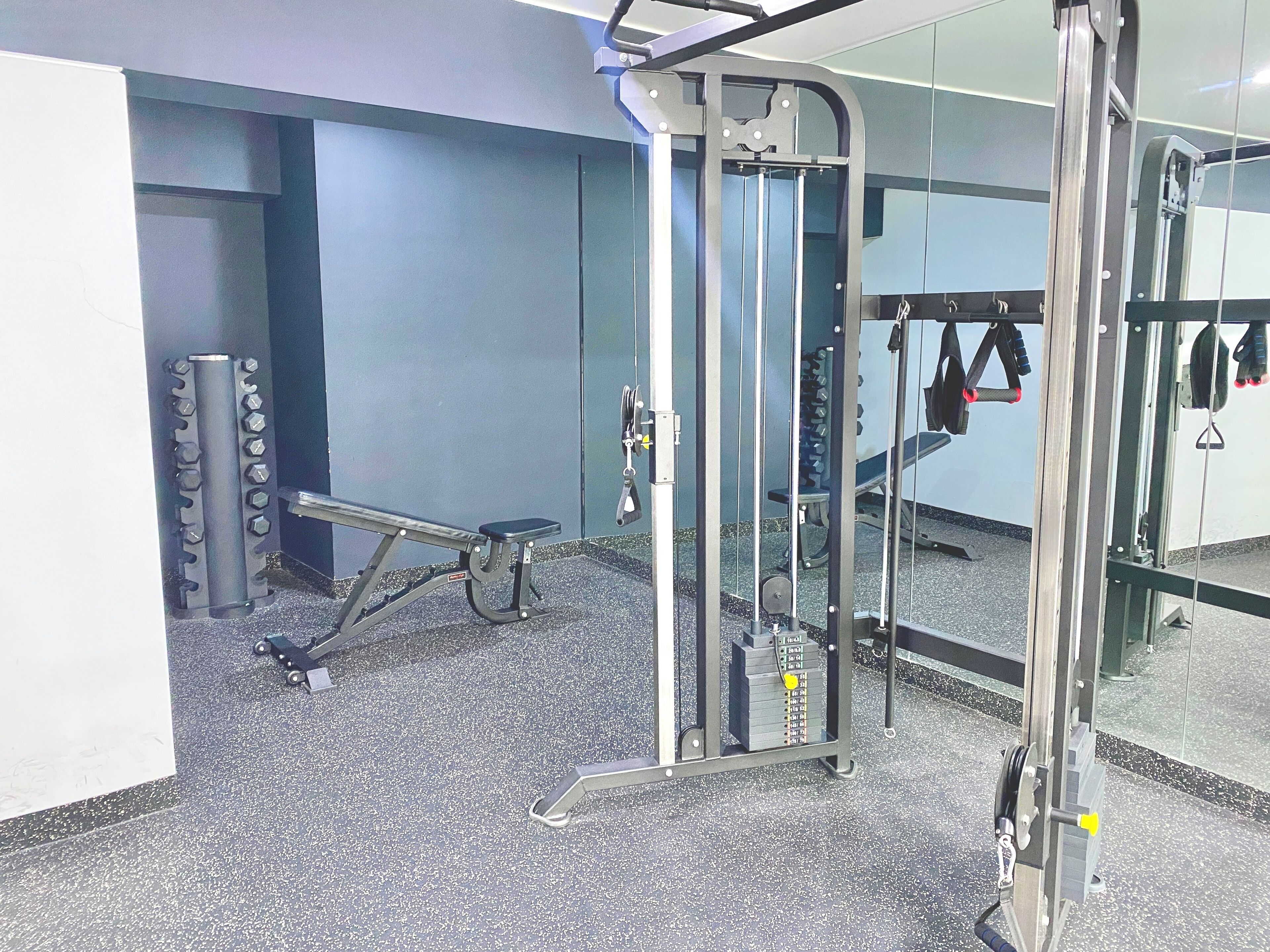 A gym with exercise equipment, a bench, and a mirrored wall.
