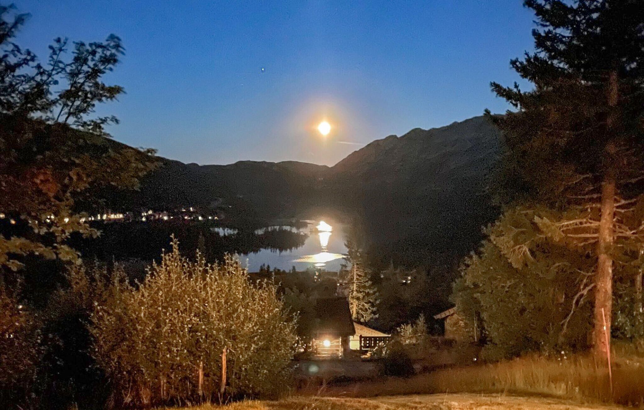 Eine Hütte mit Blick auf einen See und Berge bei Nacht.