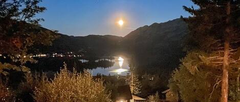 A cabin with a view of a lake and mountains at night.