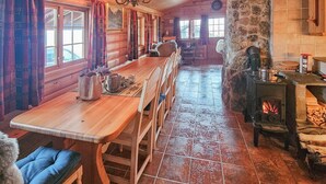 A log cabin interior with a long wooden dining table, chairs, a stone fireplace, and a tiled floor. - 4 bedroom gorgeous home in Rjukan (Rjukan)