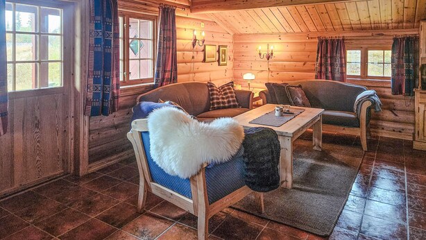 A cozy log cabin interior with two sofas, a wooden table, and a fireplace. - 4 bedroom gorgeous home in Rjukan (Rjukan)