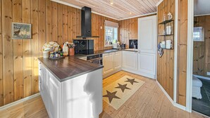A modern kitchen with wooden paneling, a central island, and a star-patterned rug. - Nice home in Rauland with WiFi (Rauland)