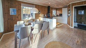 A modern kitchen with wooden walls, a dining area with grey chairs, and a central island. - Nice home in Rauland with WiFi (Rauland)