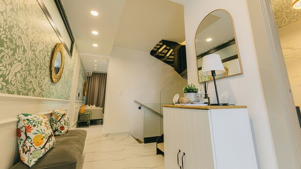 Una sala de estar moderna con un sofá, almohadones decorativos, un armario y una escalera.