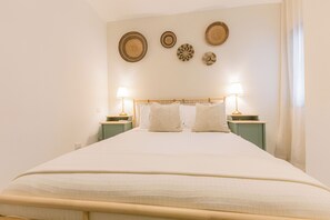 Ein ordentlich bezogenes Bett mit einem hölzernen Kopfteil, zwei Nachttischlampen und vier an der Wand hängenden Dekorationsplatten.
