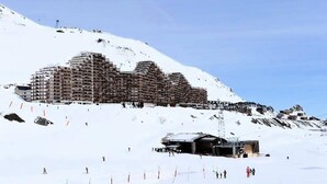 Een groot, meerlaags hotel met een modern architectuur, gelegen op een besneeuwde helling.
