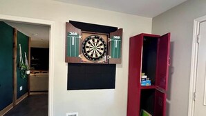 Ein Zimmer mit Dartscheibe an der Wand, einem roten Schrank und einer Tür.