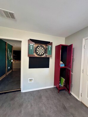 A room with a dartboard on the wall, a red cabinet, and a door. - 3 Kings! Hot Tub/Pool-Fire Pit-GameRm GYM+ PickleB (Canyon Lake)