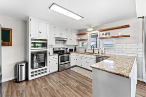 A modern kitchen with white cabinetry, stainless steel appliances, and a granite countertop. - 3 Kings! Hot Tub/Pool-Fire Pit-GameRm GYM+ PickleB (Canyon Lake)