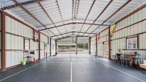 Ein überdachter Sportplatz mit Netz, Sitzgelegenheiten und Stauraumgestellen.