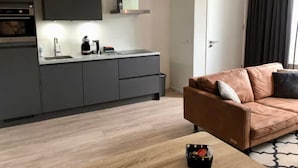 A modern kitchen with grey cabinets, a built-in oven, and a stainless steel range hood. - Beautiful Lodge Suitable for 2 People (Zoutelande)