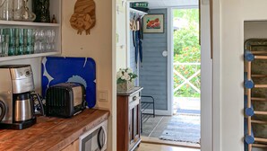 A kitchen with a coffee maker, toaster, and microwave. There is a blue suitcase on the counter and a door leading outside.