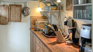 A kitchen with wooden cabinets, a coffee maker, and various kitchen utensils.