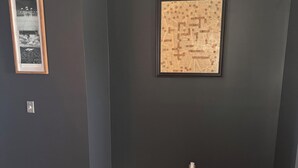 Huone, jossa on tummat seinät, puulattia ja kaksi kehystettyä taulua.