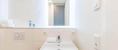 Een moderne badkamer met een rechthoekig wastafelmeubel, een spiegel en een houten blad.