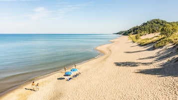 Une plage avec une eau d’un bleu limpide, un rivage sablonneux et quelques parasols.