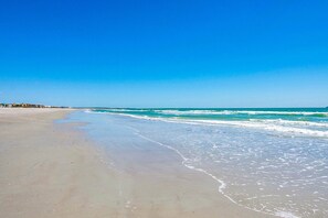 A beach with a clear sky and calm sea. - Steps to the Sea W/ Private Patio, Balcony, Fenced Backyard + BBQ Grill! 🌊 (Cape Canaveral)