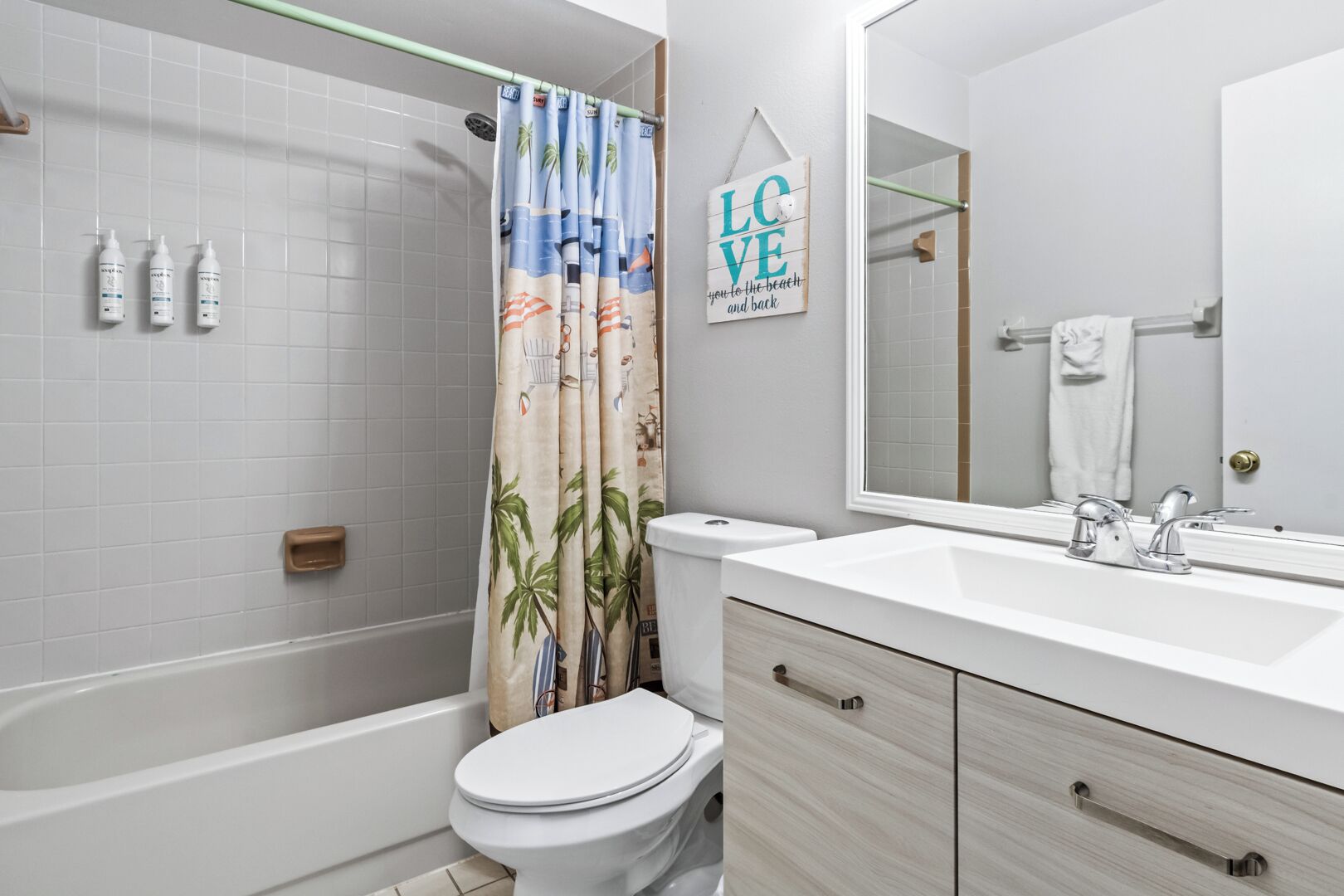 A bathroom with a shower, toilet, vanity with a mirror, and a towel rack.