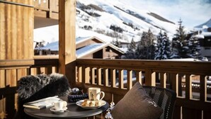 Ein Holzbalkon mit Tisch für zwei Personen mit Blick auf eine verschneite Berglandschaft.